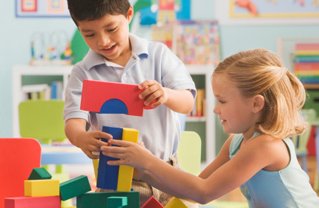 Two kids building a tower with blocks